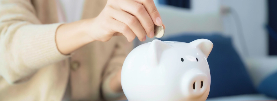 woman putting coin in piggy bank to represent wealth management