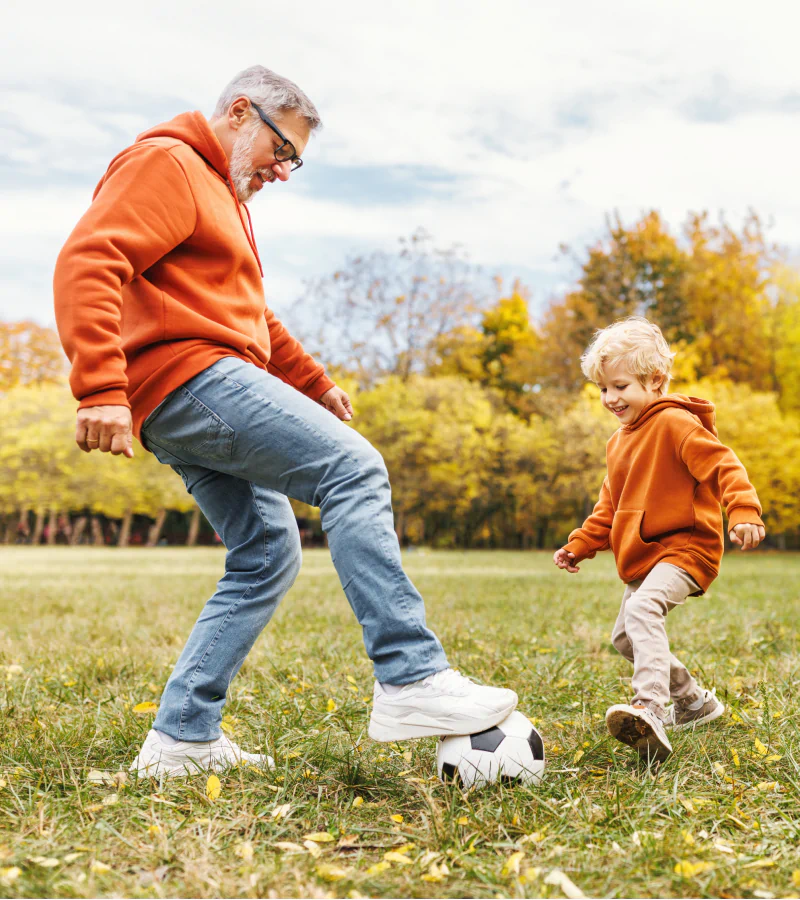grandfather and grandson in matching hoodies playing with soccer ball