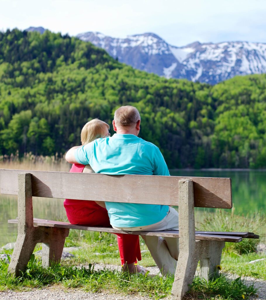 senior couple sitting together on bench outdoors retirement strategies beacon financial williston vt 910x1024