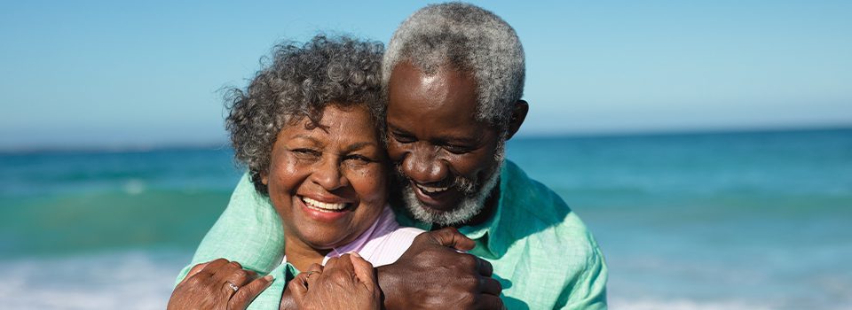 smiling senior couple ebracing on beach annuity basics beacon financial williston vt